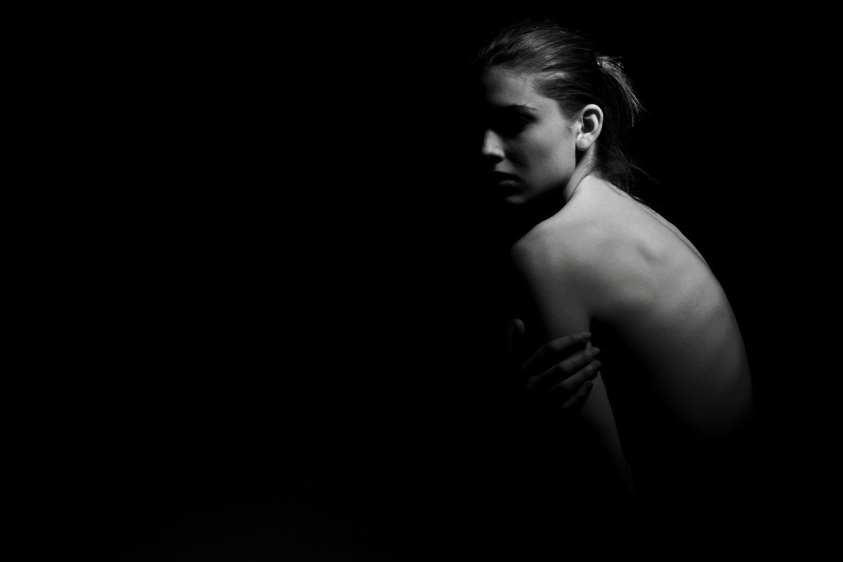 slim and naked woman on black background